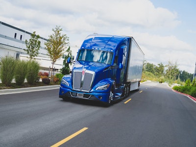 A blue Kenworth T680 hauling a trailer.