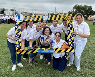 A group of people hold up a giant, safety-themed picture frame.
