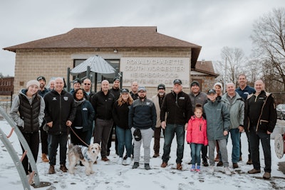 A group of people stands in the snow in front of a community center.