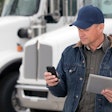 Man with phone and tablet near a truck