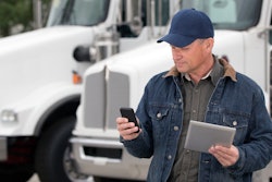 Man with phone and tablet near a truck