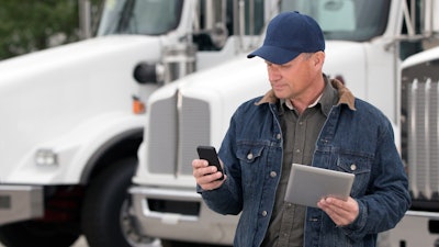 Man with phone and tablet near a truck
