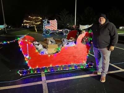 A man stands next to a sleigh full of donations.