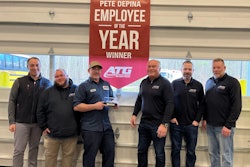 Six men stand around a flag that says 'Pete DePina Employee of the Year winner' with the ATG logo.