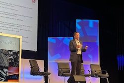 A man stands on a stage discussing strategic decision making and operational strategy.