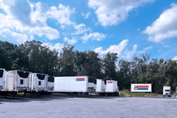 Trailers sit on a yard under a blue sky.