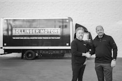 Two men shake hands in front of a Bollinger Motors truck.