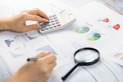 A hand with forms, a calculator and a magnifying.