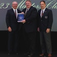 Three men from NationaLease stand on a stage holding an award.