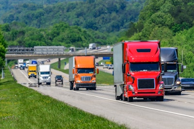 Several trucks on highway with traffic