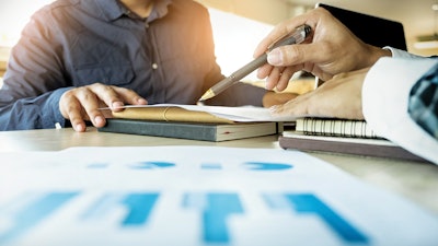 Man using pen to show data on a sheet to customer