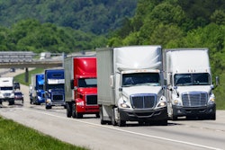 Group of trucks on a highway with trees in background