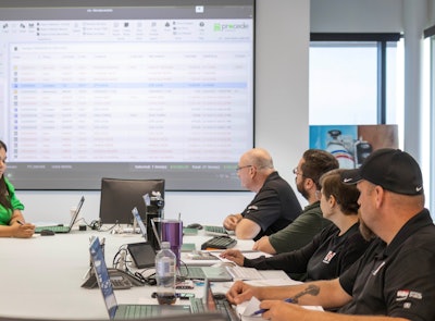 People at a conference table looking at the Procede software on a screen