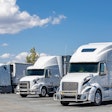 Three white trucks in a lot