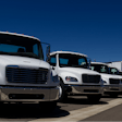 Line of white used trucks in a parking lot