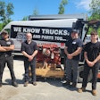 A group of men standing in front of an engine on a forklift.