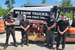A group of men standing in front of an engine on a forklift.