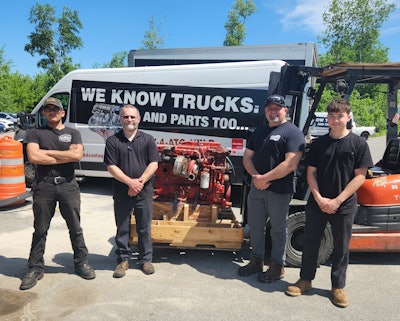 A group of men standing in front of an engine on a forklift.