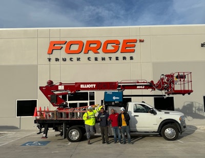 A sign crew stands in front of a truck in front of a concrete building that reads Forge Truck Centers