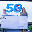 Two people hold a large check for $10,000 in front of a screen.