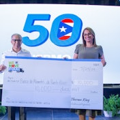 Two people hold a large check for $10,000 in front of a screen.
