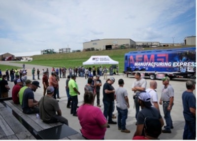 A crowd of people in front of Felling Trailers and the AEM Manufacturing Express bus.