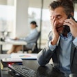 Frustrated man looking at a computer on the phone
