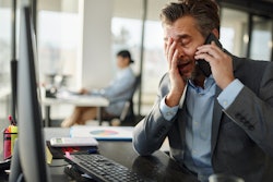 Frustrated man looking at a computer on the phone