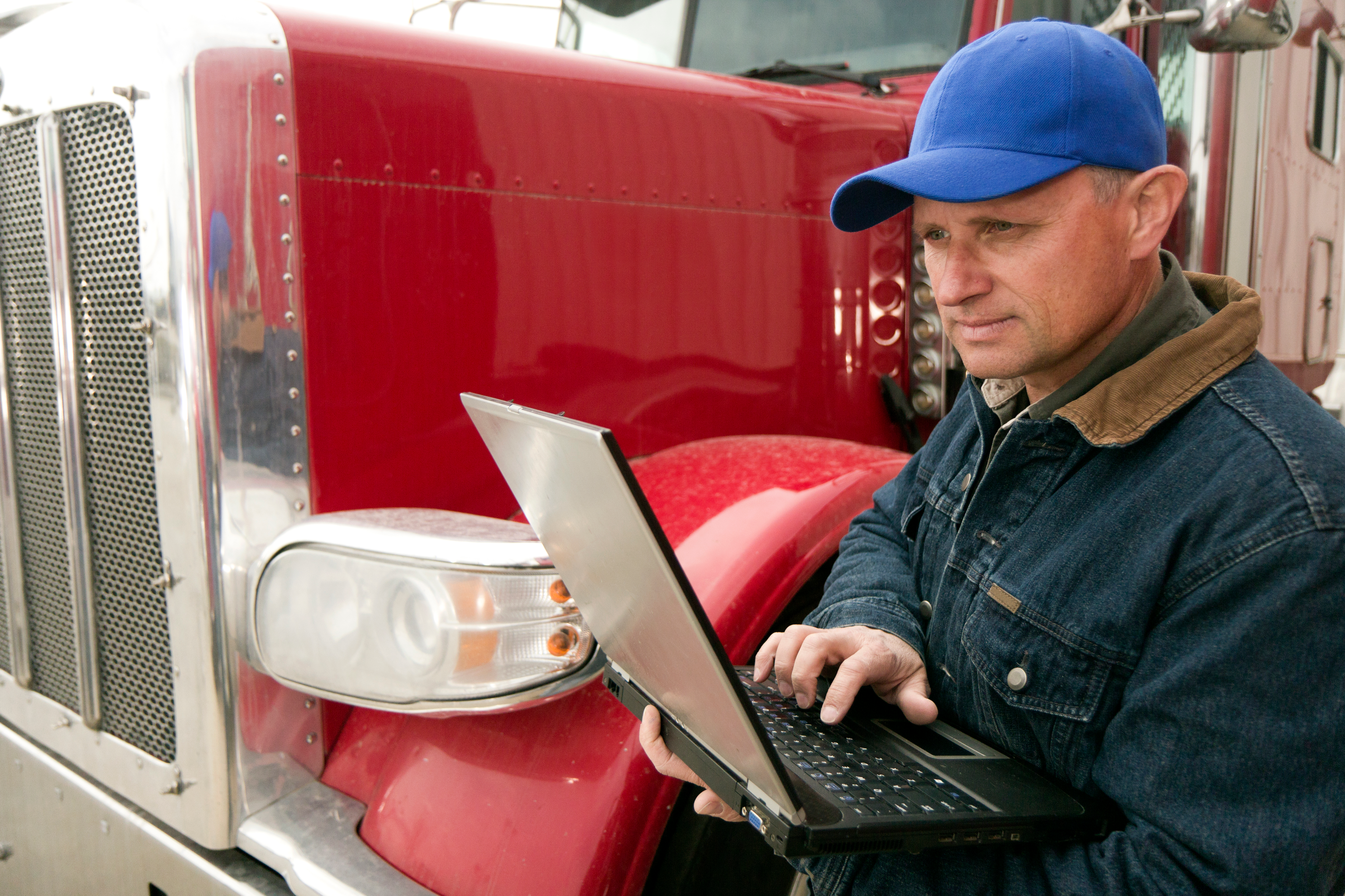 Man holding laptop while standing by truck