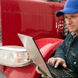 Man holding laptop while standing by truck