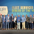 A group of people stand on stage in front of a Paccar Parts/Peterbilt banner.