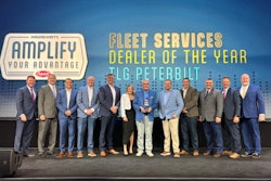 A group of people stand on stage in front of a Paccar Parts/Peterbilt banner.