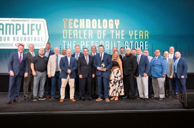 A group of people stand on a stage in front of a Paccar Parts/Peterbilt banner.