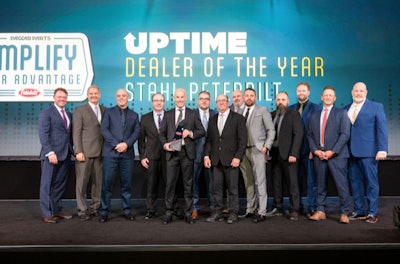A group of people stand on stage in front of a Paccar Parts/Peterbilt banner.