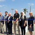 A group of people cutting a blue ribbon in front of a Nikola truck.