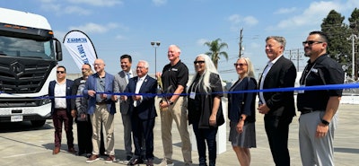 A group of people cutting a blue ribbon in front of a Nikola truck.