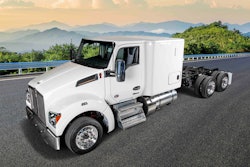 A white Kenworth sleeper cab without a trailer and mountains in the background.