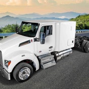 A white Kenworth sleeper cab without a trailer and mountains in the background.