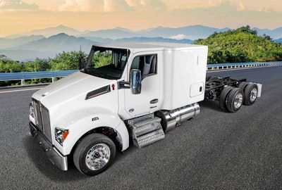 A white Kenworth sleeper cab without a trailer and mountains in the background.