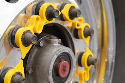 A yellow LUG LINX system sits on lug nuts on a truck wheel.