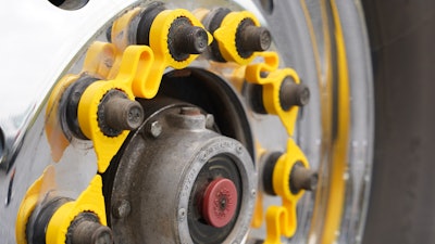 A yellow LUG LINX system sits on lug nuts on a truck wheel.