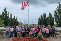 A group of people in front of a flag pole.