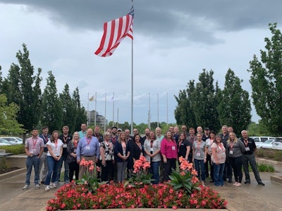 A group of people in front of a flag pole.