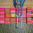 A ship full of multicolored cargo containers is moored under a blue crane at the port of Jacksonville, Florida.