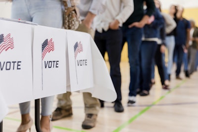 A line of people stand in line to vote.