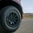 A front tire on a red truck on the road.