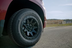 A front tire on a red truck on the road.