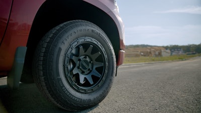 A front tire on a red truck on the road.