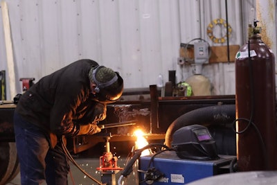 A man welds a piece of machinery