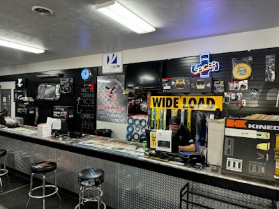 A man works behind a counter with a computer and signage